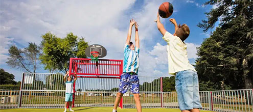 Enfants jouant au basket sur le terrain multisports du camping Domaine du Logis