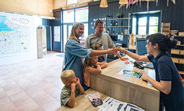 Une famille à la réception du camping Domaine du Logis