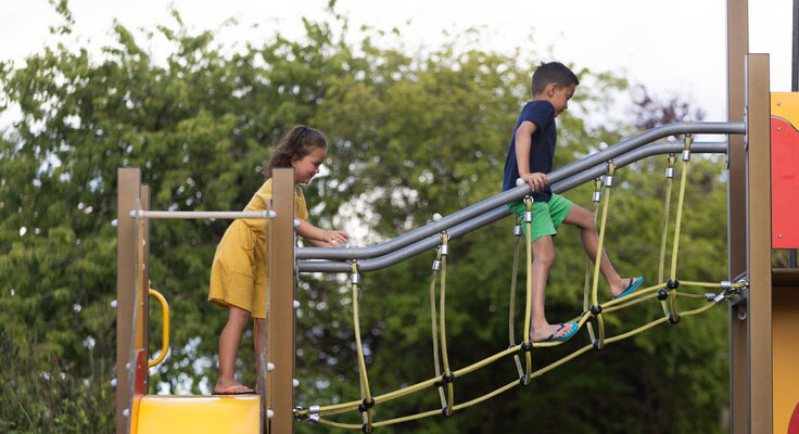 Les enfants s'amusent sur l'aire de jeux du camping Domaine du Logis
